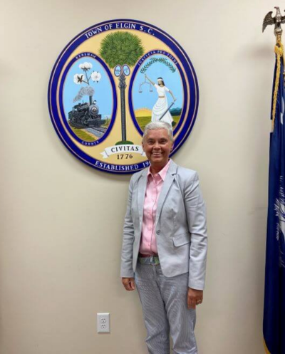 Melissa Emmons stands in front of town of elgin seal